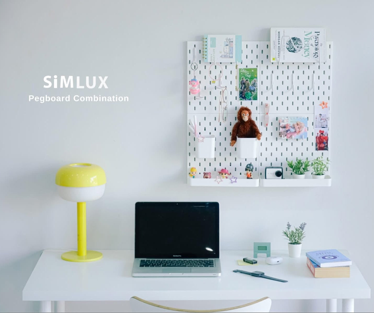 Pegboard combination on a wall above a desk with a laptop, lamp, and books.